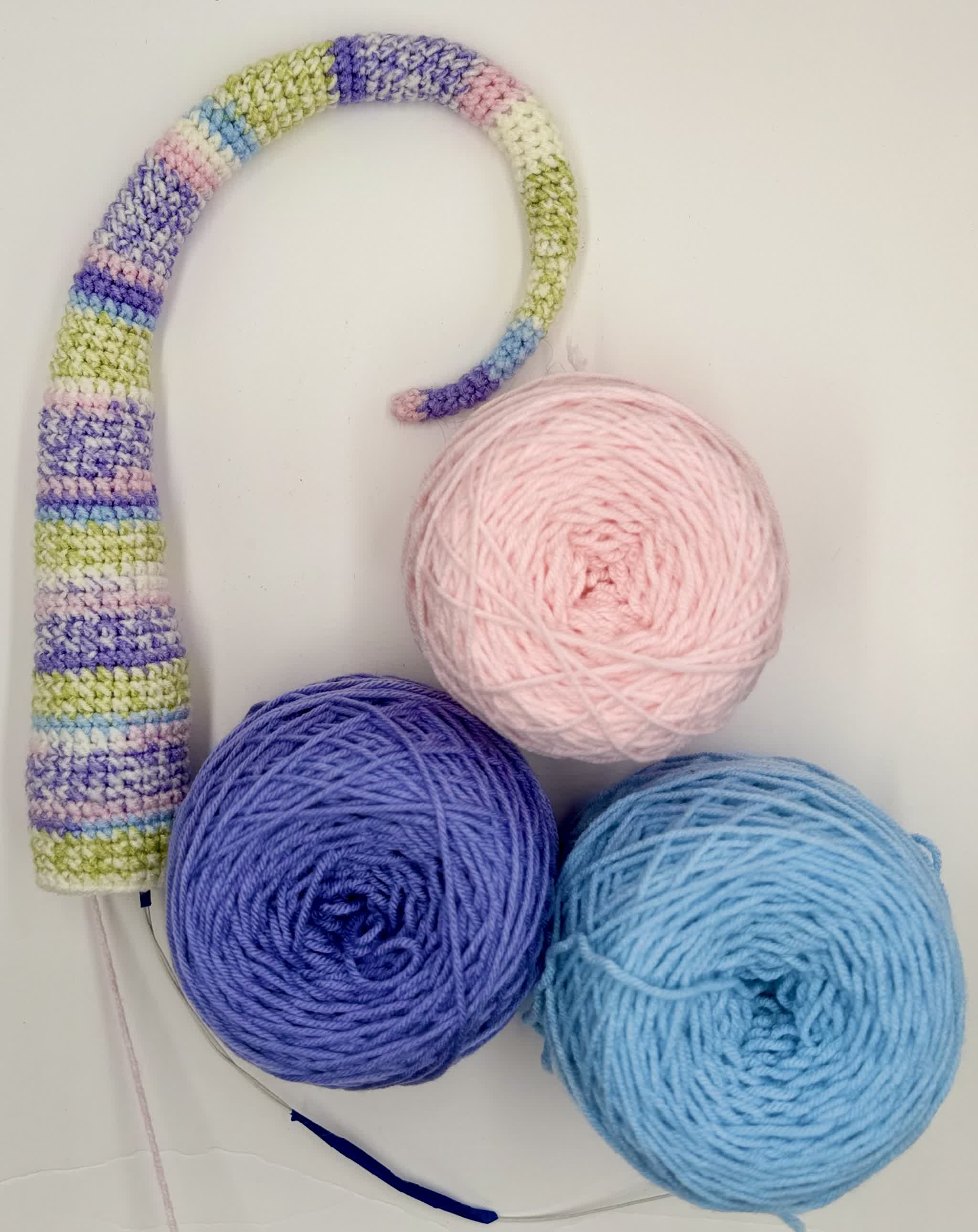 Crochet dragon tail with three pastel accent-color yarn cakes